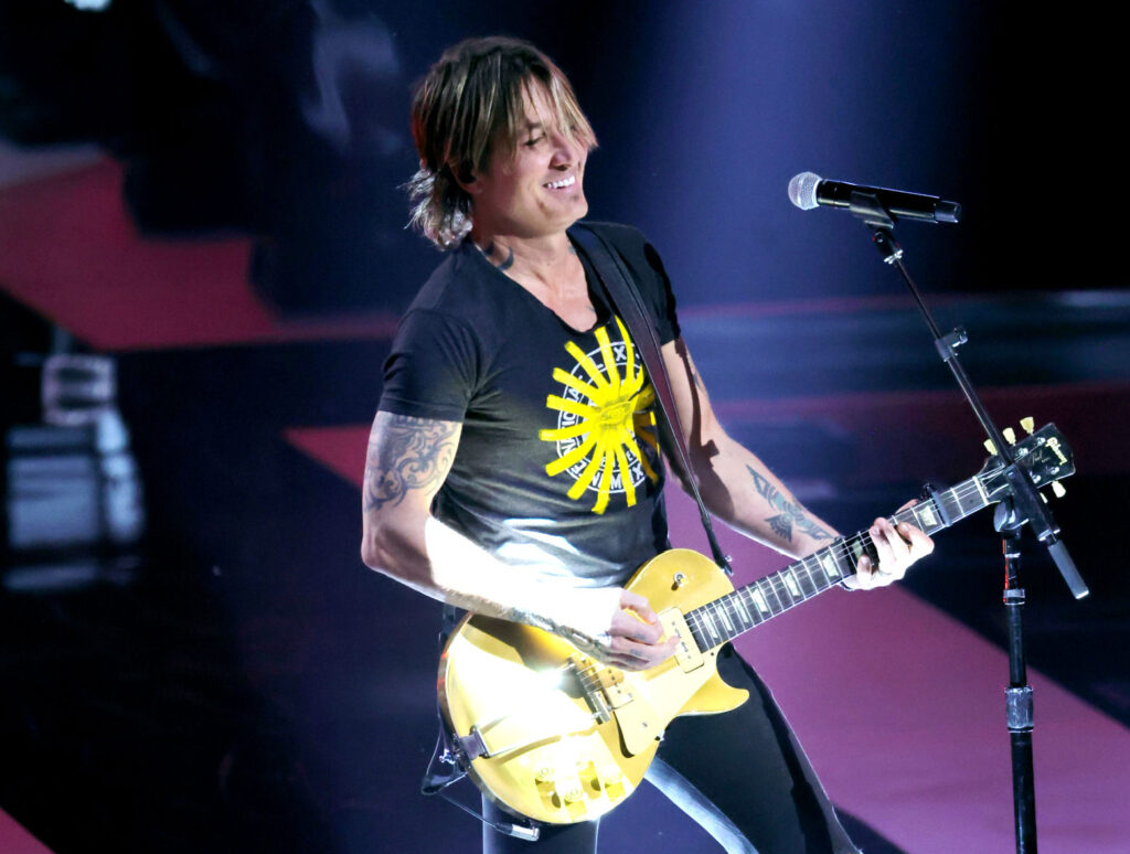 All-Time Kings Of Country Music - Keith Urban playing guitar on stage wearing black.