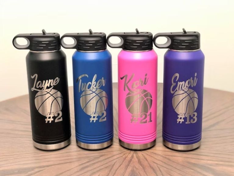 four laser engraved water bottles with different names and sports numbers on it.