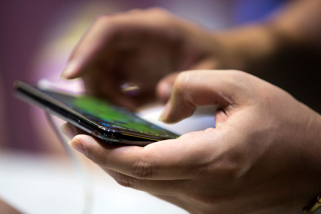 A booth attendant plays a video game on a smartphone