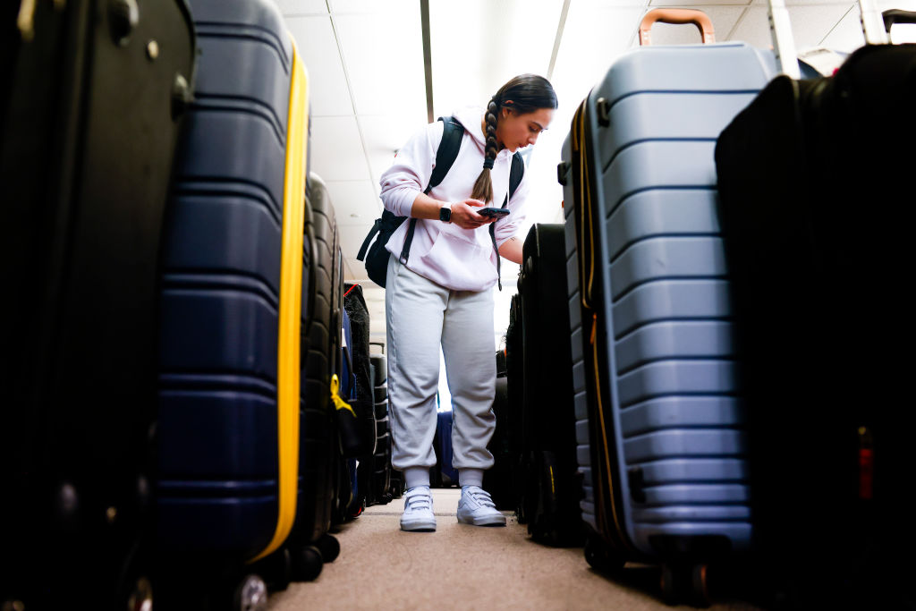 Pristine Floyde searches for a friend's suitcase in a baggage holding area