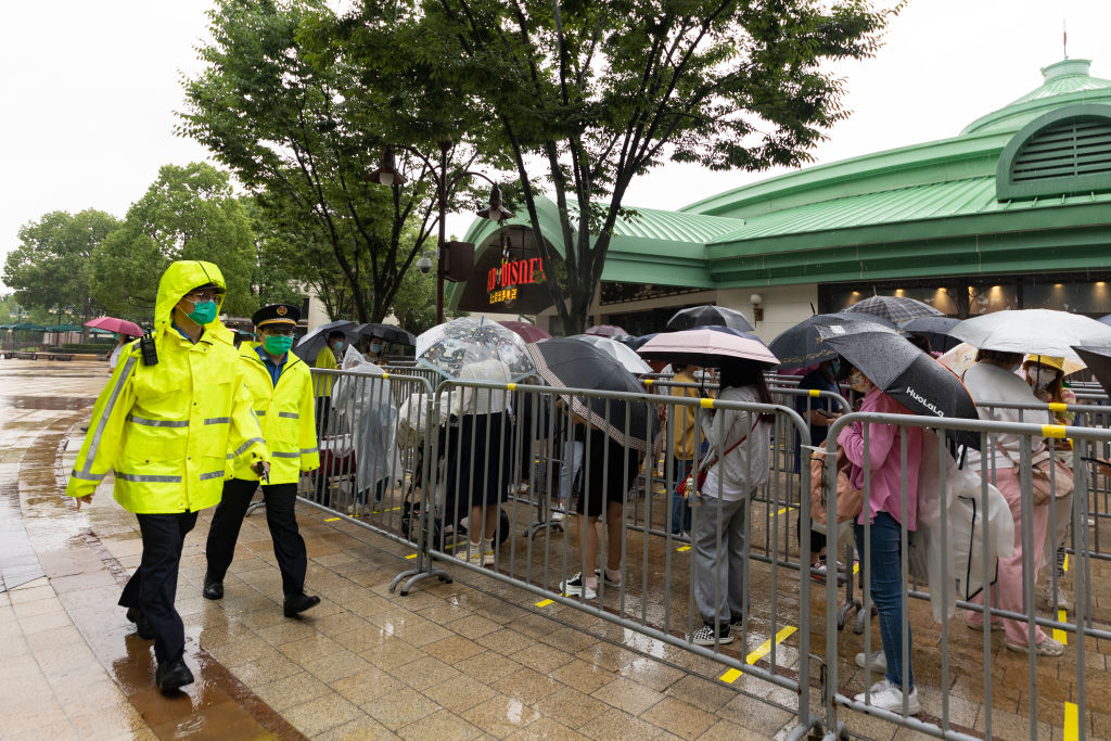 Security staff patrol as visitors wait in line to enter a store at Shanghai Disney Resort on June 10, 2022 in Shanghai, China. Shanghai Disney Resort is resuming partial operations, with reduced capacity and opening hours, as COVID-19 cases ease in the city.